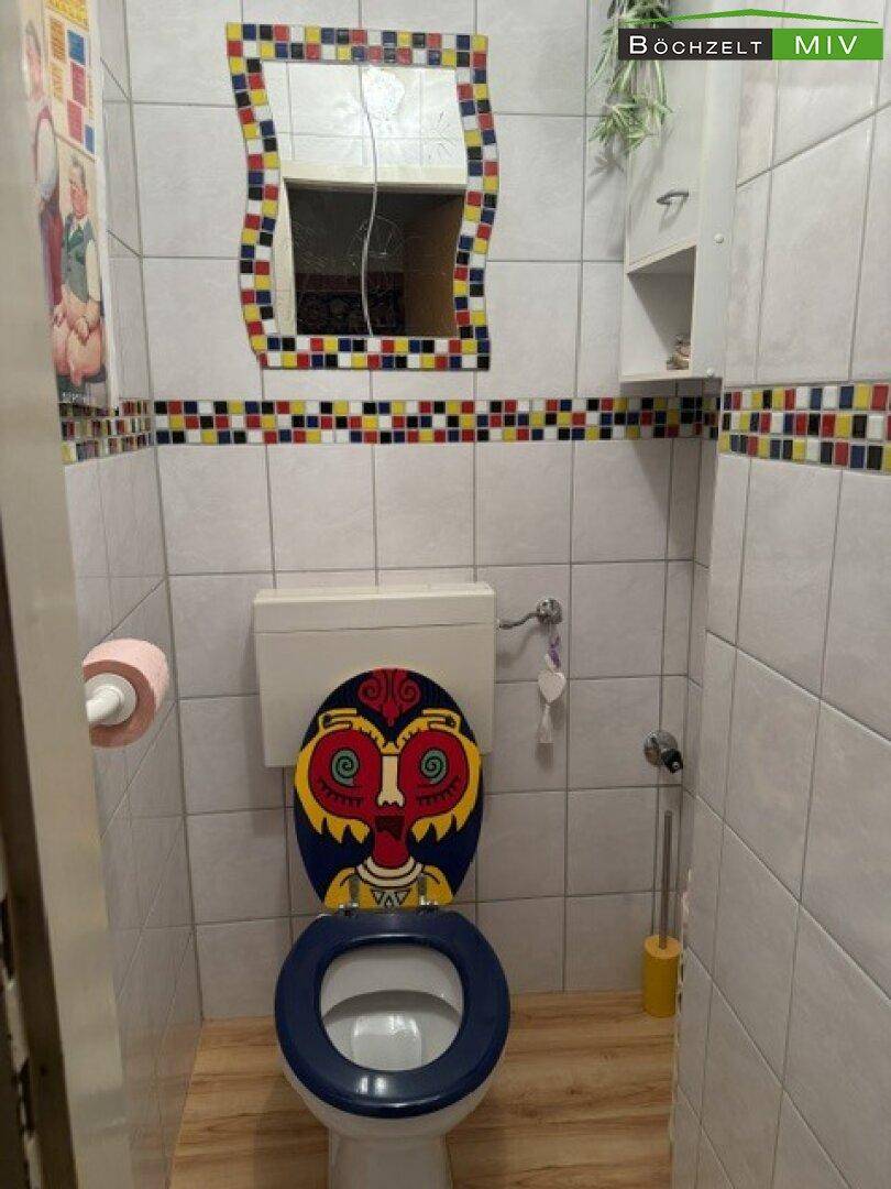 Separates WC mit farbenfroher Dekoration und Fliesenboden.