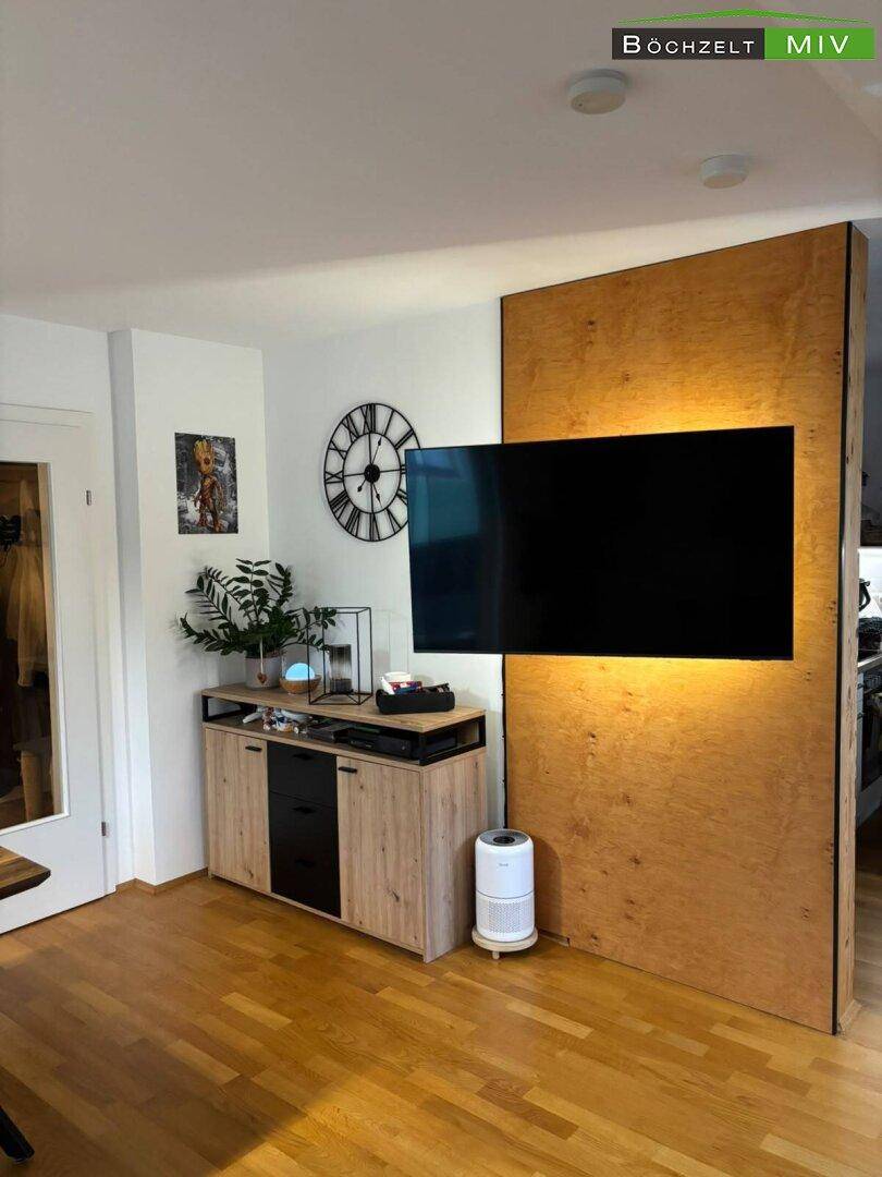 Moderner Wohnbereich mit Holzboden und an der Wand montiertem Fernseher, stilvoll und funktional gestaltet.