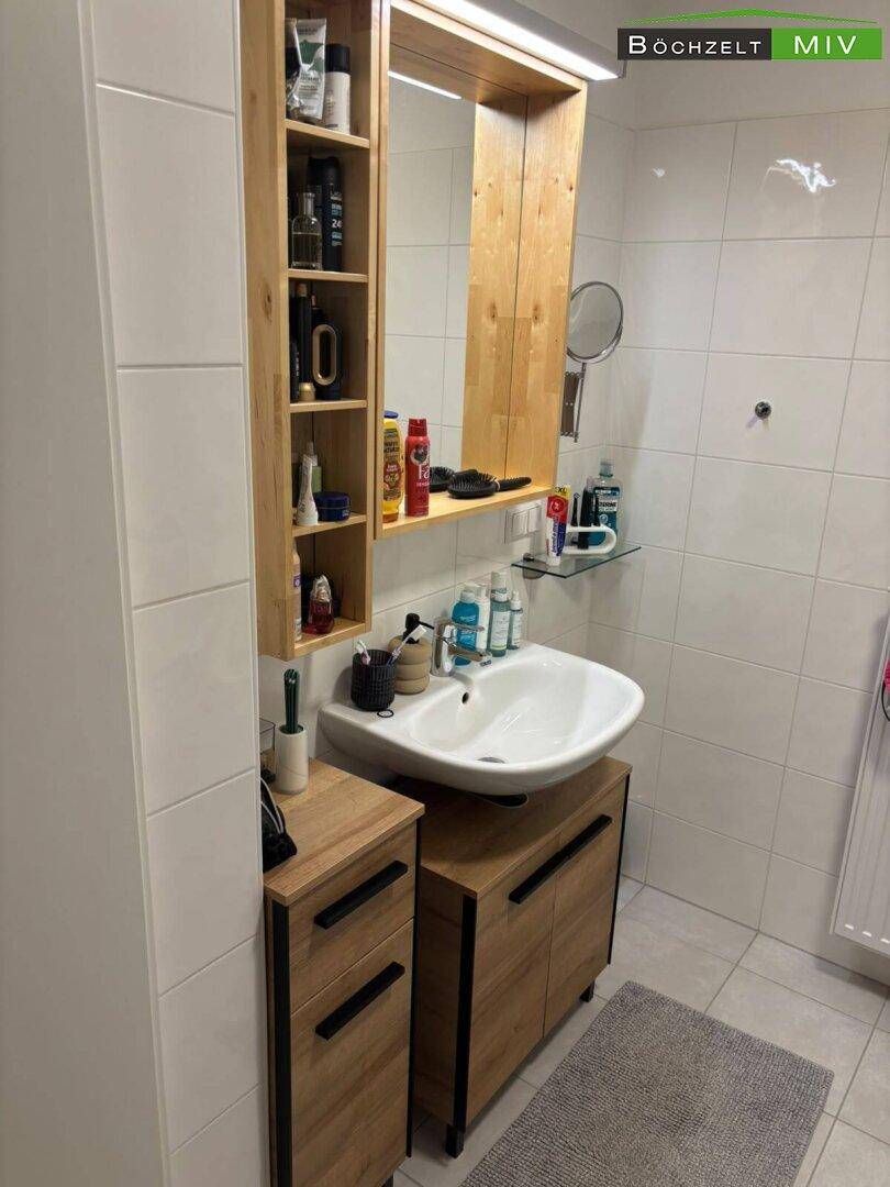 Modernes Badezimmer mit Waschbecken, Spiegelschrank und hellen Fliesen, funktional und sauber.