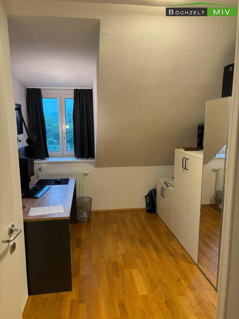 Arbeitszimmer im Dachgeschoss mit Schreibtisch, Holzboden und Fenster, bietet einen ruhigen Arbeitsplatz.