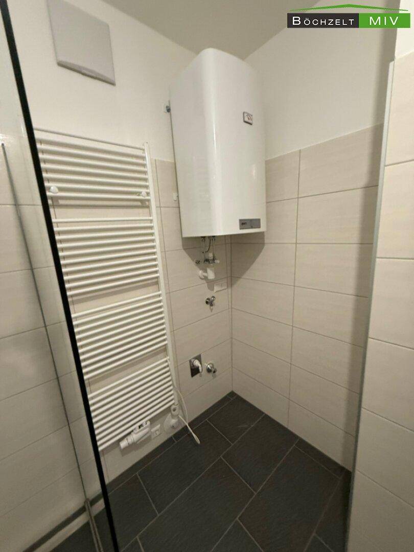 Detailansicht des Badezimmers mit beheiztem Handtuchhalter und Warmwasserboiler.