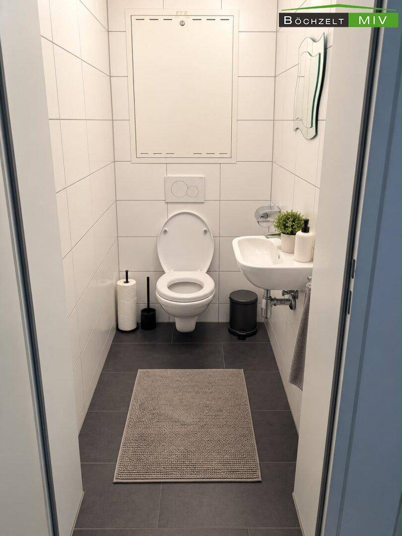 Separates Gäste-WC mit Wand-WC, kleinem Waschbecken und weißen Wandfliesen.