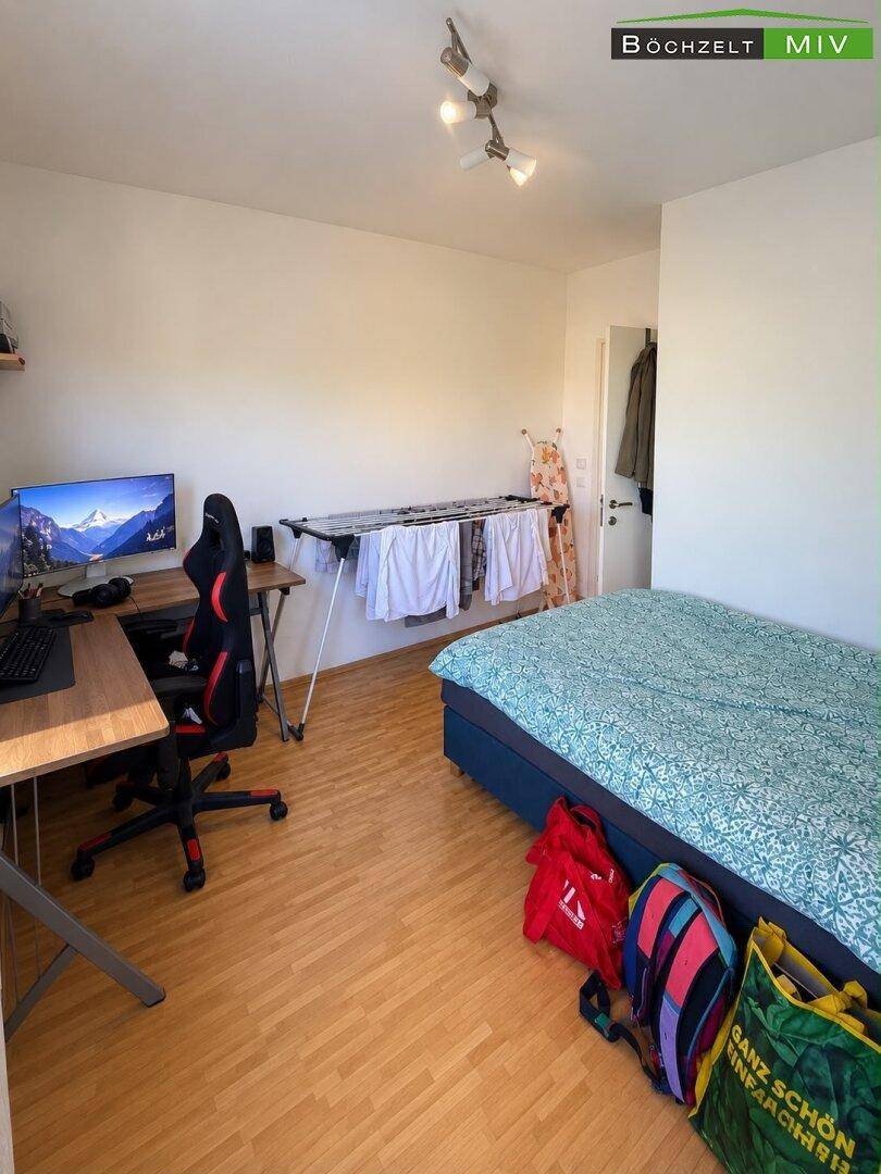 Helles Zimmer mit Holzboden, Schreibtisch und Einzelbett, ideal als Gäste- oder Arbeitszimmer.