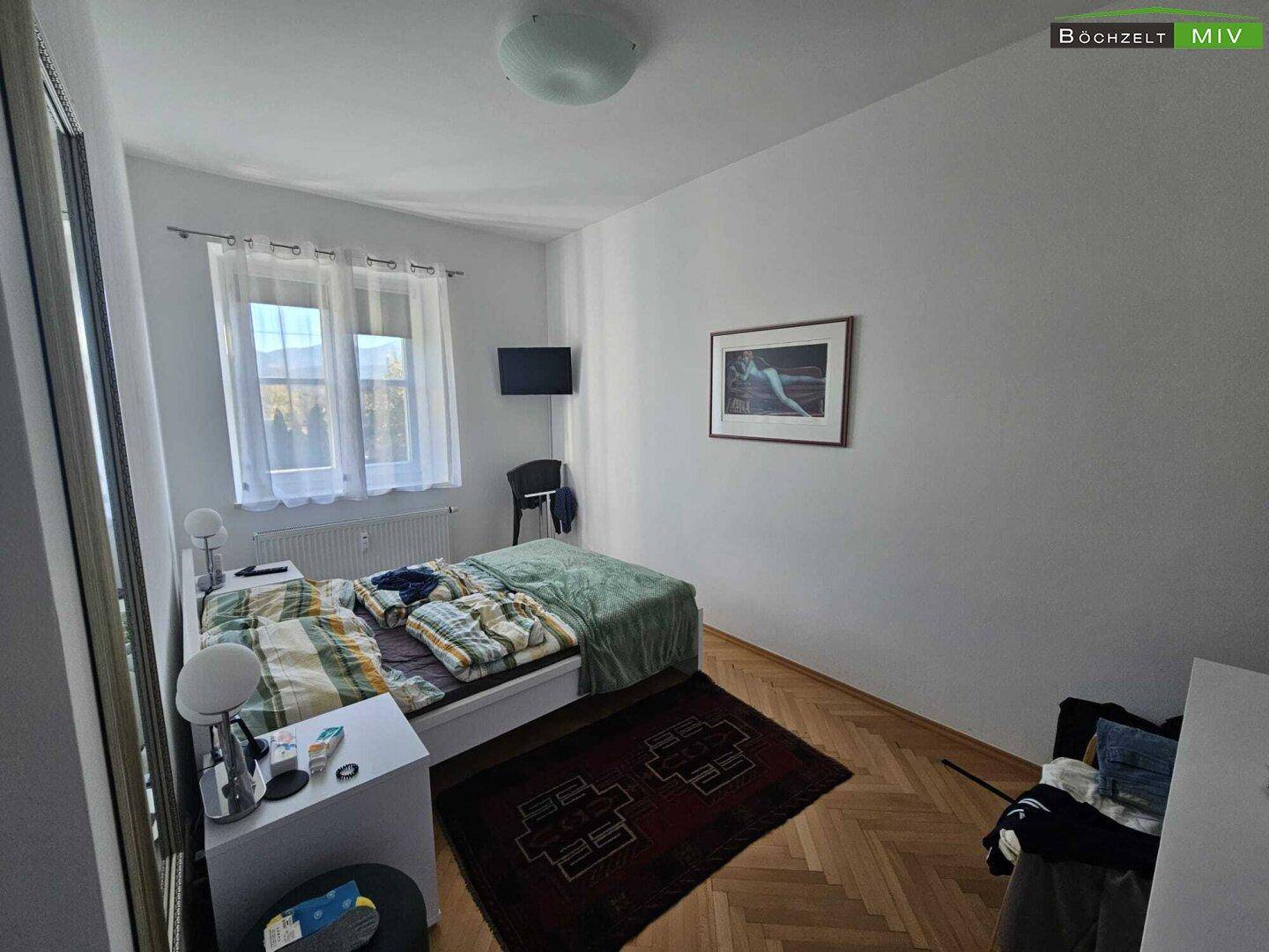 Gemütliches Schlafzimmer mit Einzelbett, Nachttisch und Fischgrätparkettboden.