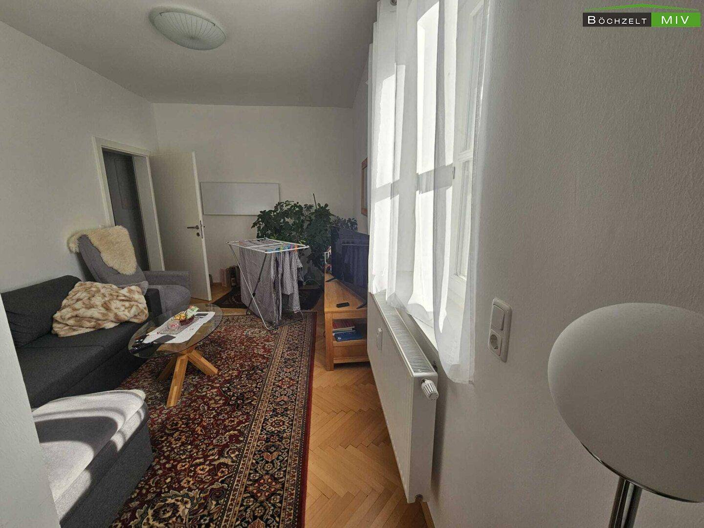 Wohnzimmer mit Sofa, Couchtisch und großem Fenster für viel Tageslicht.