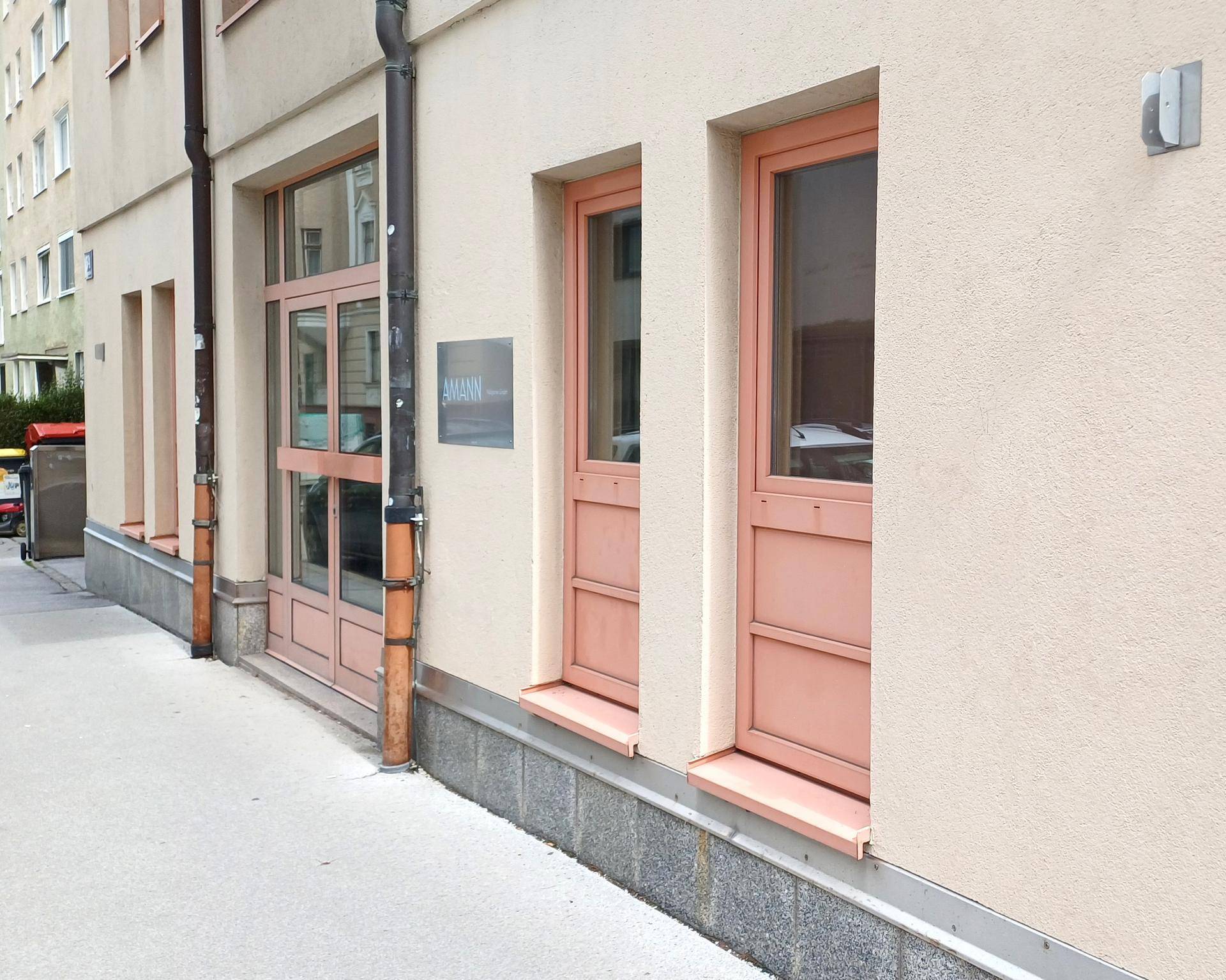 Fassadenansicht des Gebäudes im Erdgeschoss mit Fenstern und einem Eingangsbereich.