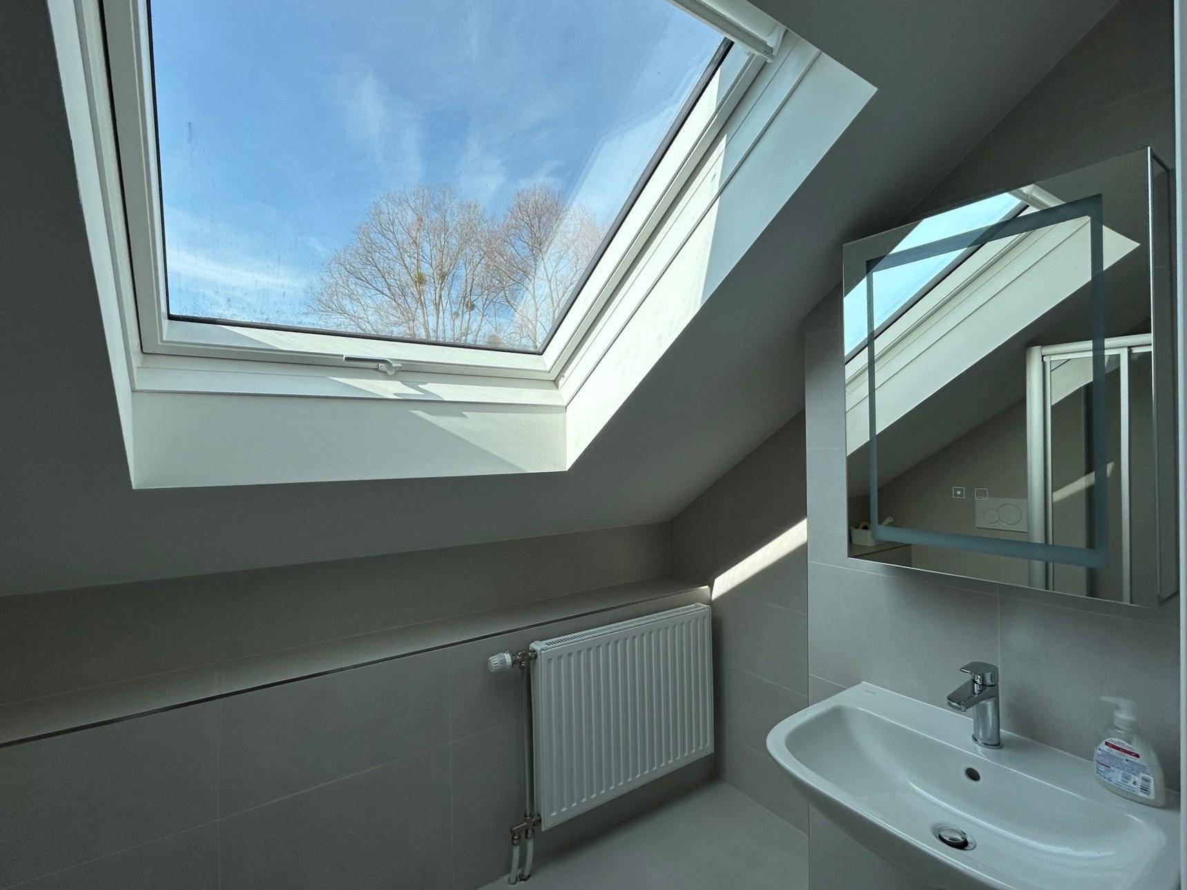 Helles Badezimmer im Dachgeschoss mit Waschbecken, Spiegelschrank und Dachfenster.