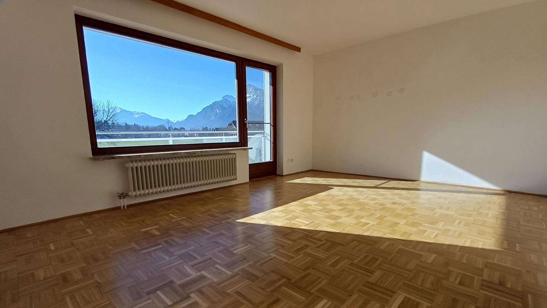 Helles Wohnzimmer mit Parkettboden und weitem Blick auf die umliegende Berglandschaft.