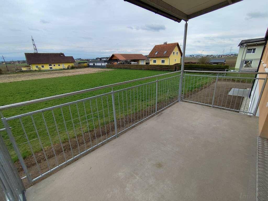 Geräumiger Balkon mit Metallgeländer und weitem Blick über die ländliche Umgebung.