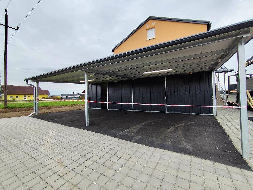 Überdachter Carport-Bereich mit mehreren Stellplätzen und gepflasterter Zufahrt.