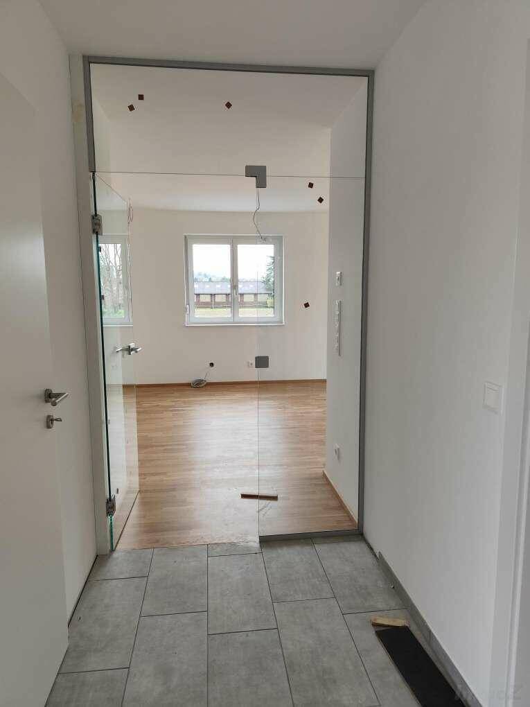 Heller Eingangsbereich mit Fliesenboden und moderner Glastür zum Wohnbereich.