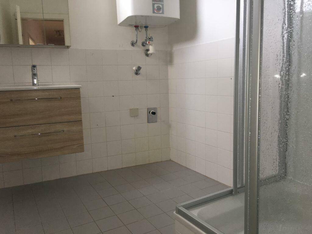 Badezimmer mit Duschkabine, Waschbeckenunterschrank und Wandfliesen.