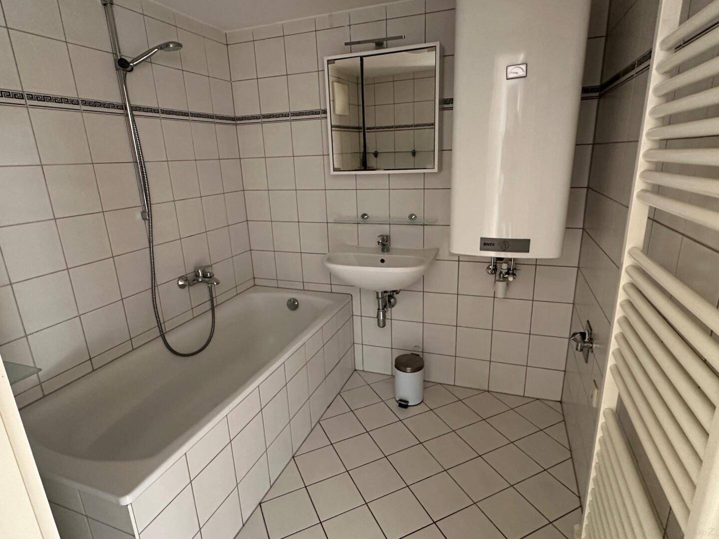 Badezimmer mit Badewanne, Fliesenboden und Wandfliesen in klassischem Design.