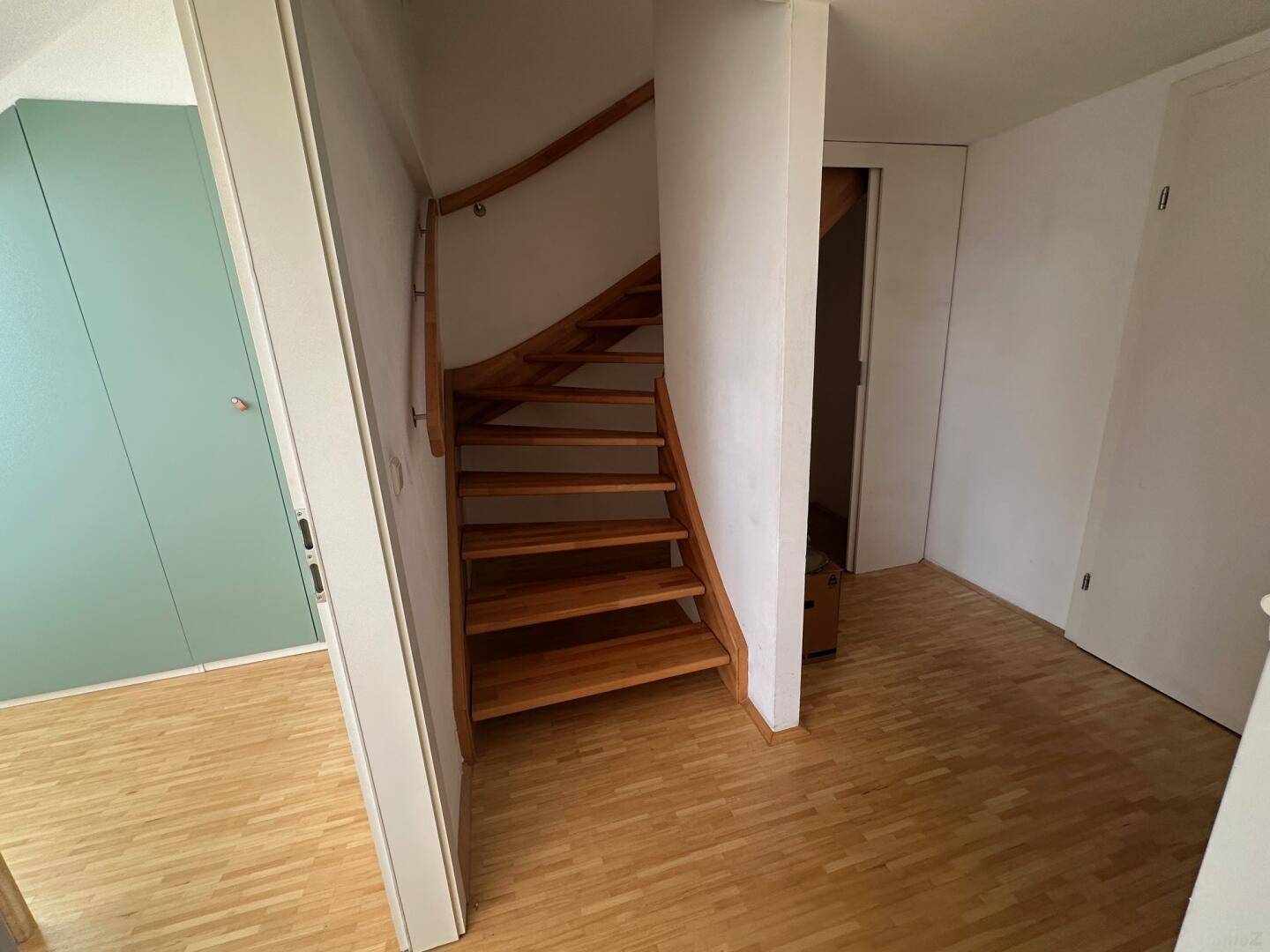 Heller Flur mit Holztreppe und Holzboden, der die verschiedenen Ebenen verbindet.