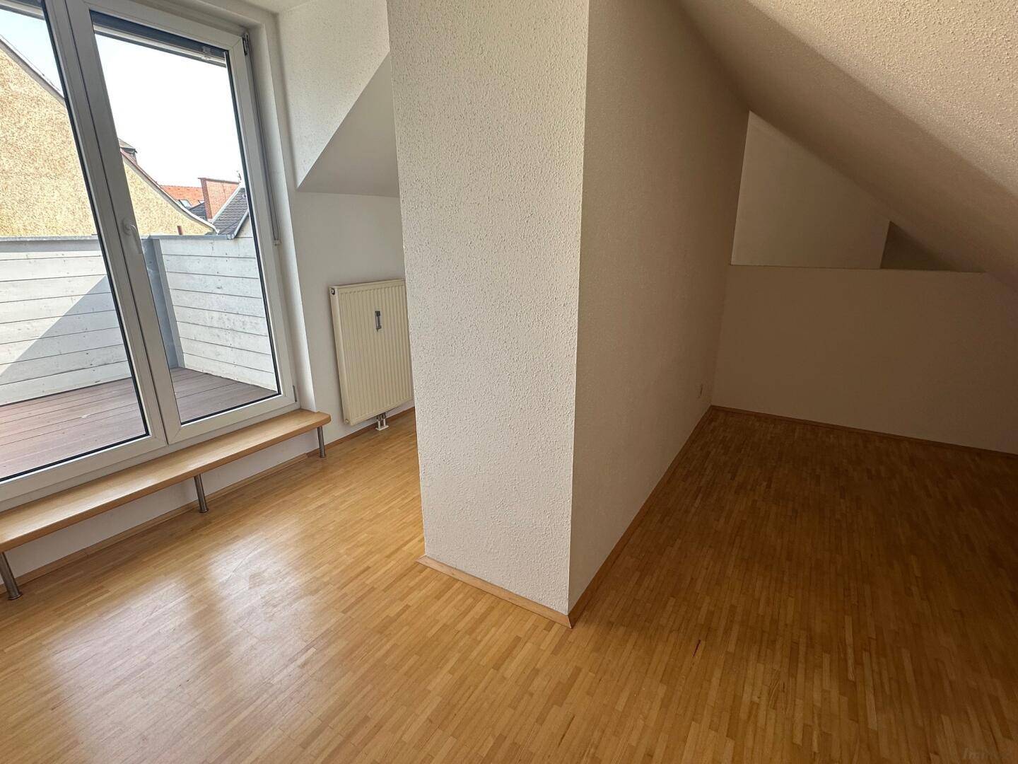 Geräumiger Wohnbereich mit Holzboden, Dachschrägen und viel Tageslicht.