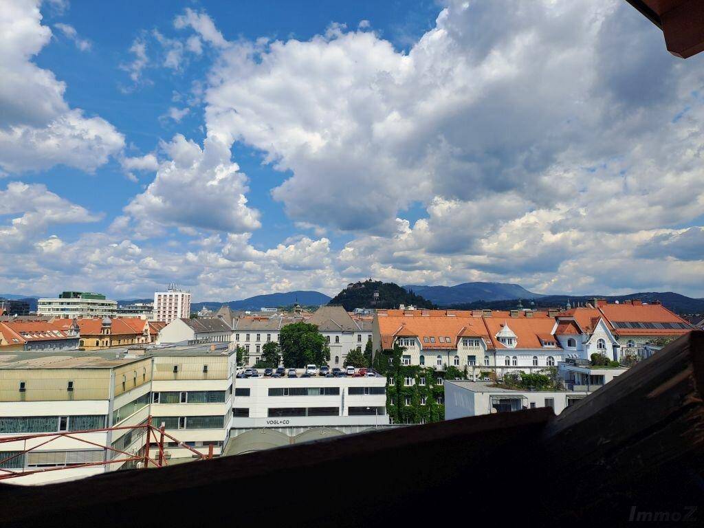 Panoramablick über die Stadt mit Bergen im Hintergrund unter blauem Himmel.