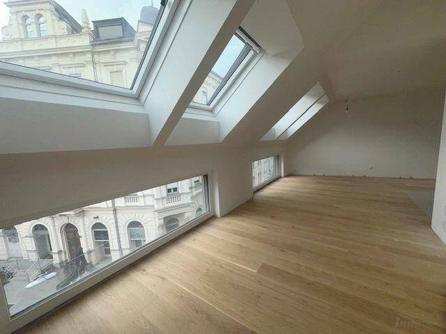 Heller Dachbodenraum mit Holzboden, schrägen Wänden und mehreren Dachfenstern, bereit zum Ausbau.