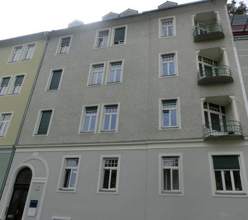 Fassade eines Mehrfamilienhauses mit Balkonen und klassischen Fenstern.