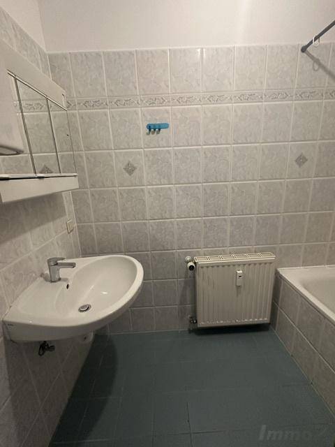 Badezimmer mit hellen Fliesen, Waschbecken und Badewanne.