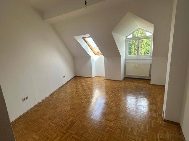 Helles Schlafzimmer im Dachgeschoss mit Parkettboden und schrägen Wänden.