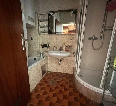 Badezimmer mit Badewanne, Duschkabine, Waschbecken und gemusterten Fliesen.