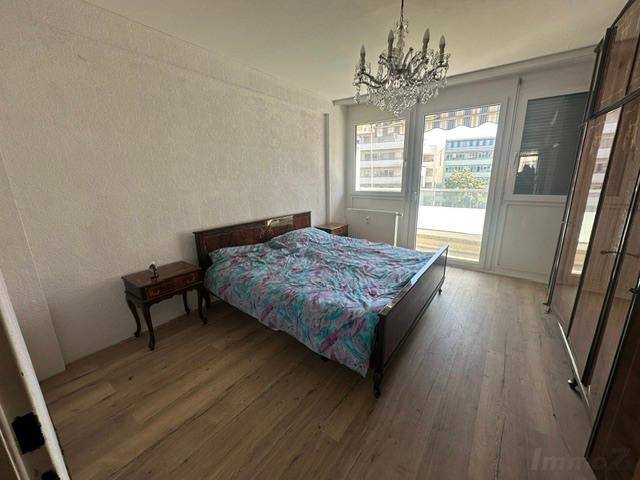 Schlafzimmer mit Doppelbett, Laminatboden und großen Fenstern für viel Tageslicht.