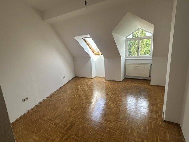 Helles Schlafzimmer mit Parkettboden, Dachschrägen und einem Dachfenster für viel Tageslicht.