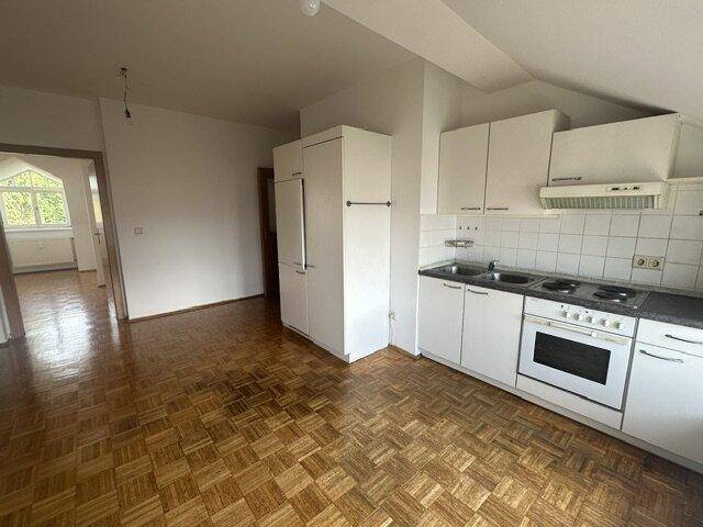 Funktionale Küche mit weißen Schränken, Herd und Kühlschrank, ausgestattet mit Parkettboden.