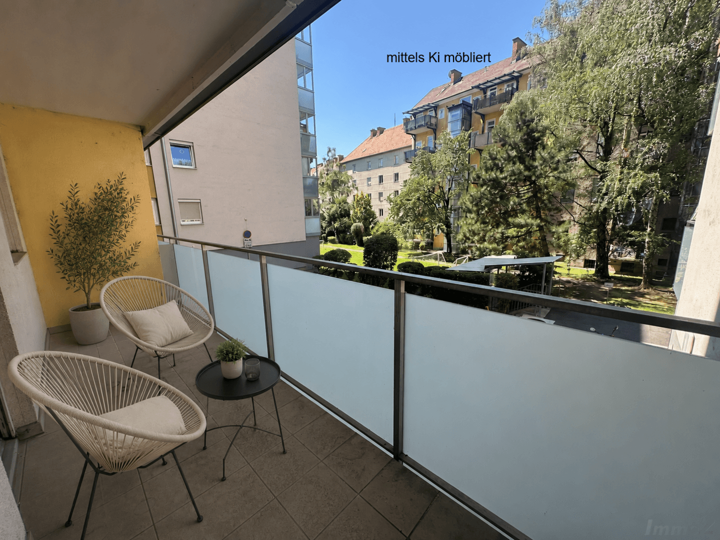 Möblierter Balkon mit Blick auf einen grünen Innenhof und umliegende Gebäude.