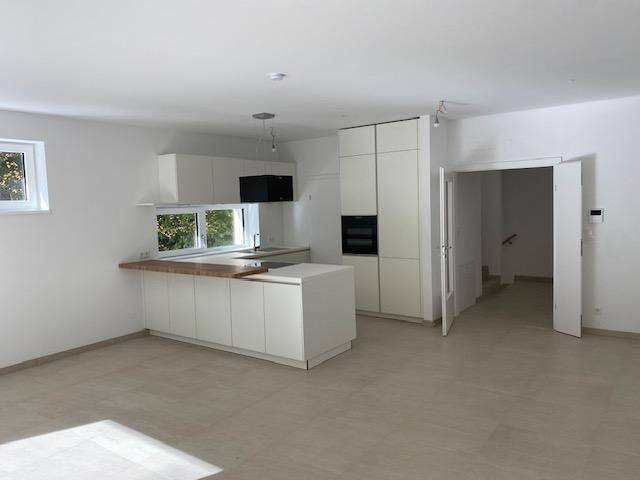Offene Küche mit weißen Schränken und Holztheke, angrenzend an den Wohnbereich.