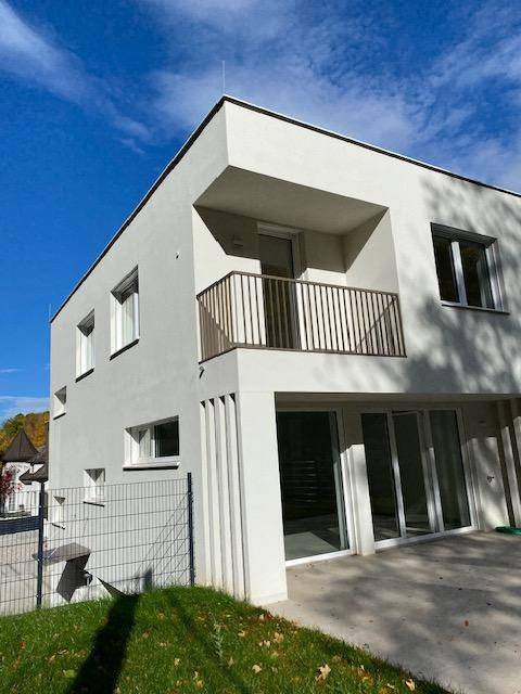 Moderne Architektur der Doppelhaushälfte mit Balkon und großen Fensterfronten.