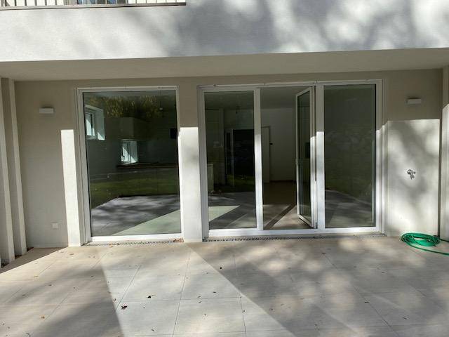 Geräumige Terrasse mit Fliesenboden und Zugang zum Innenbereich durch große Glastüren.