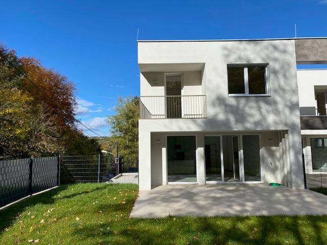 Ansicht der modernen Doppelhaushälfte mit Balkon und Terrasse im Herbst.