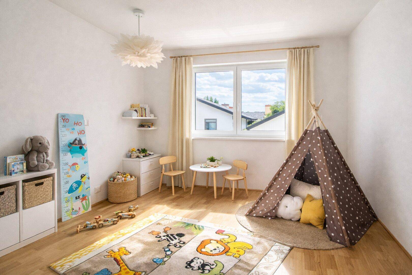Helles Kinderzimmer mit Holzboden, Spielteppich, kleinem Tisch und Fensterblick.