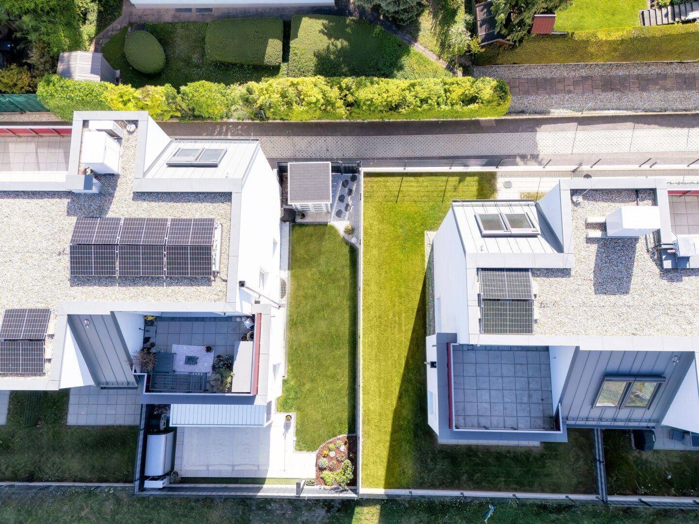 Luftaufnahme von modernen Gebäuden mit Flachdächern, Solaranlagen und schmalen Gärten.