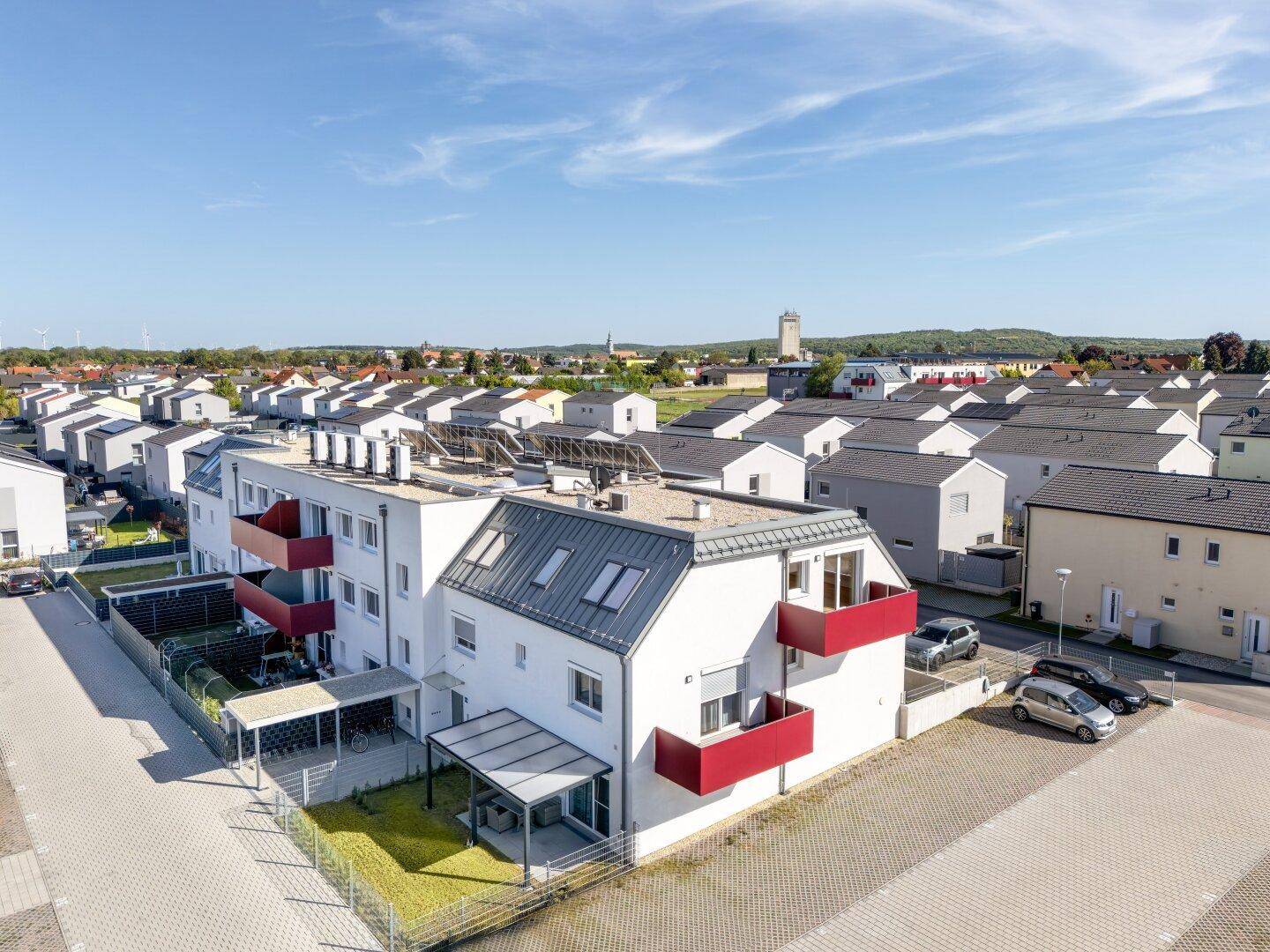 Überblick aus der Vogelperspektive über eine Wohnanlage mit modernen Gebäuden und Parkplätzen.