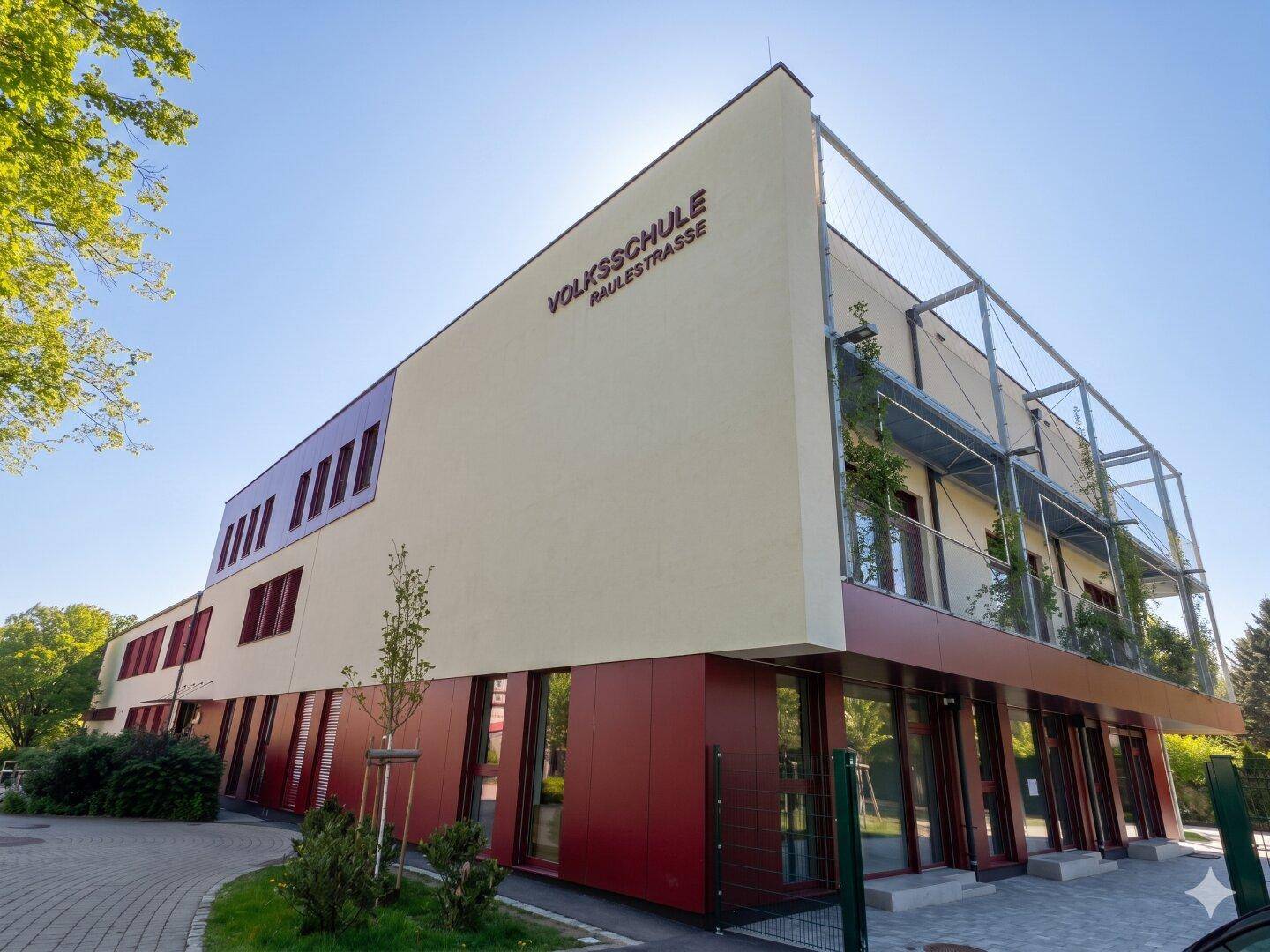 Modernes Schulgebäude "Volksschule Raulesstrasse" mit großen Fenstern und zeitgenössischer Architektur.