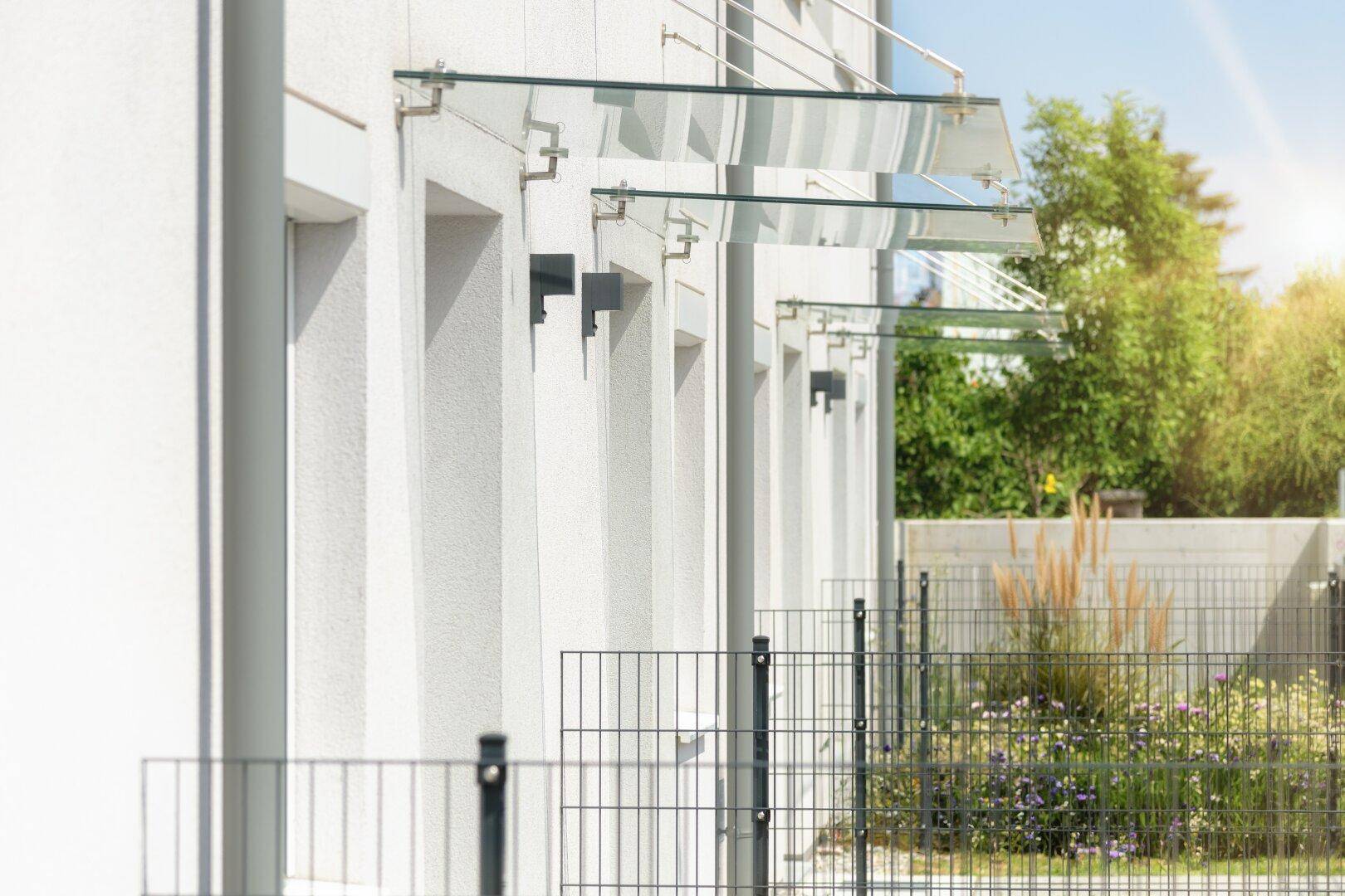 Moderne Gebäudefassade mit schützenden Glasvordächern über den Eingängen.