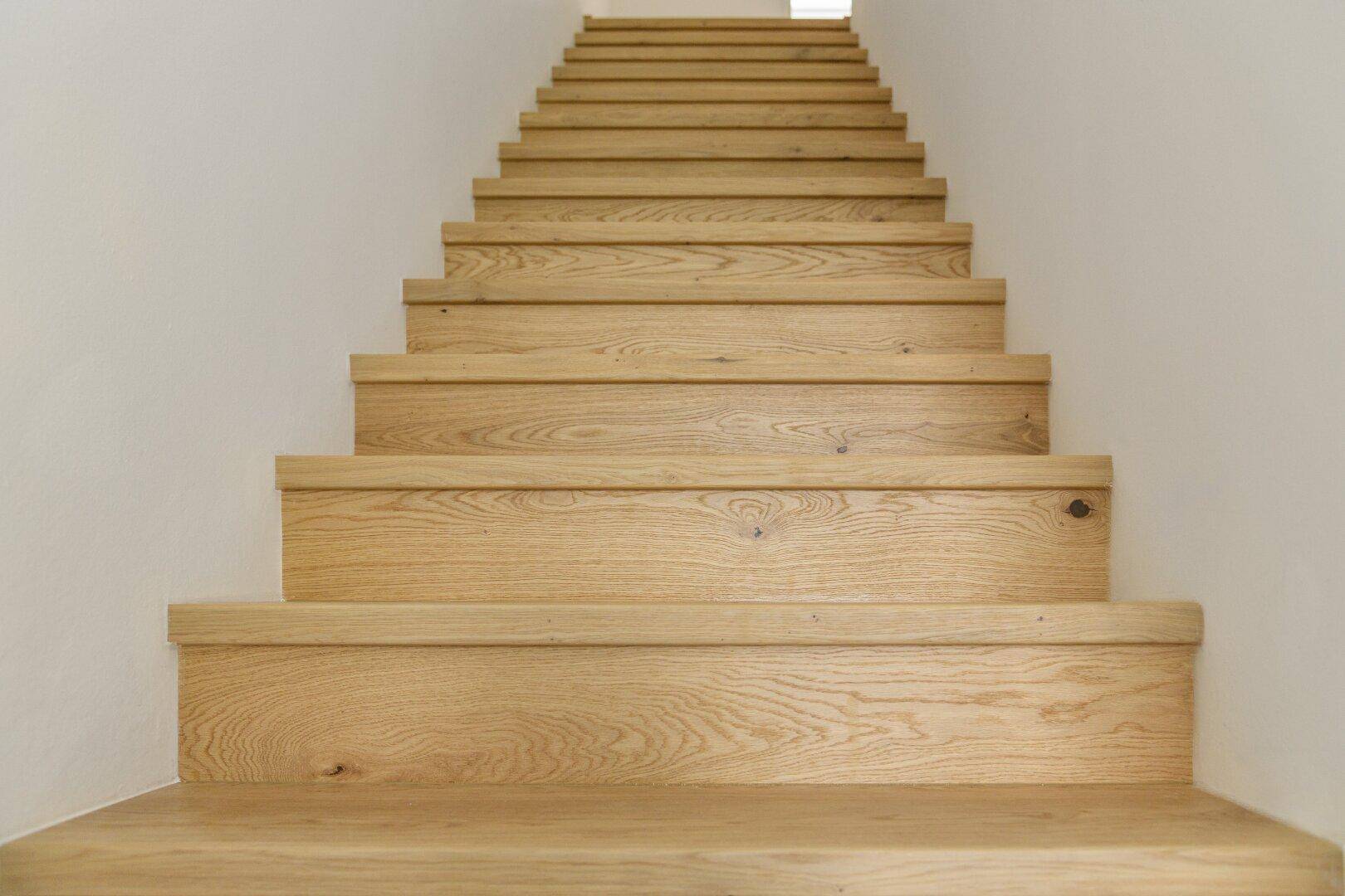 Helle Holztreppe mit schlichtem Design, die die verschiedenen Etagen des Hauses verbindet.