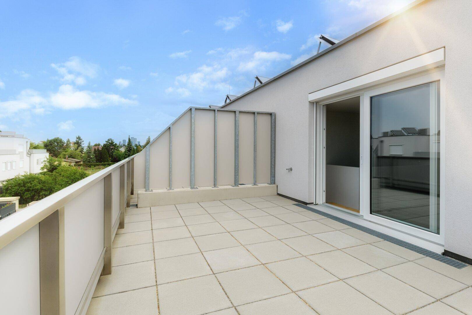 Großer gefliester Balkon mit Metallgeländer und Schiebetür, ideal für sonnige Stunden im Freien.