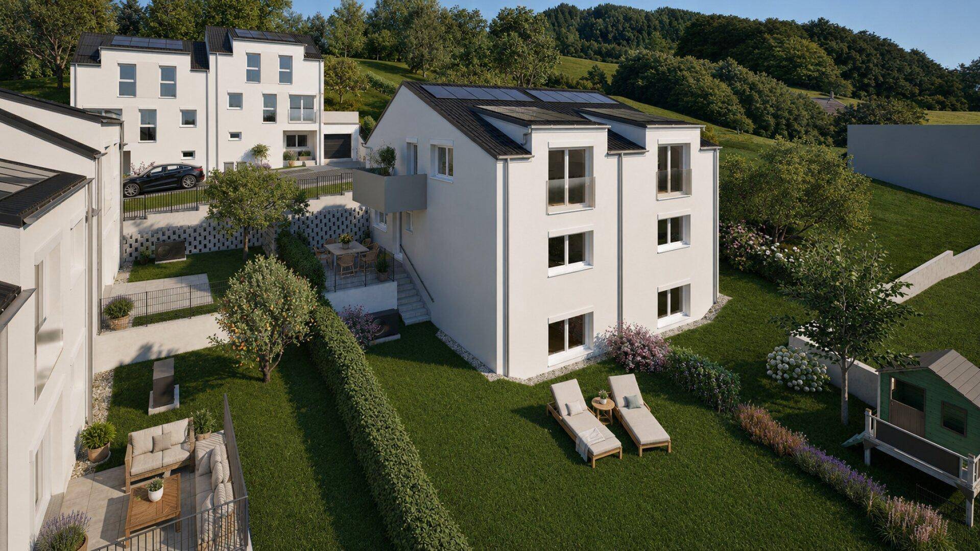 Mehrere moderne Häuser mit Gärten und Terrassen in einer grünen, hügeligen Wohngegend.