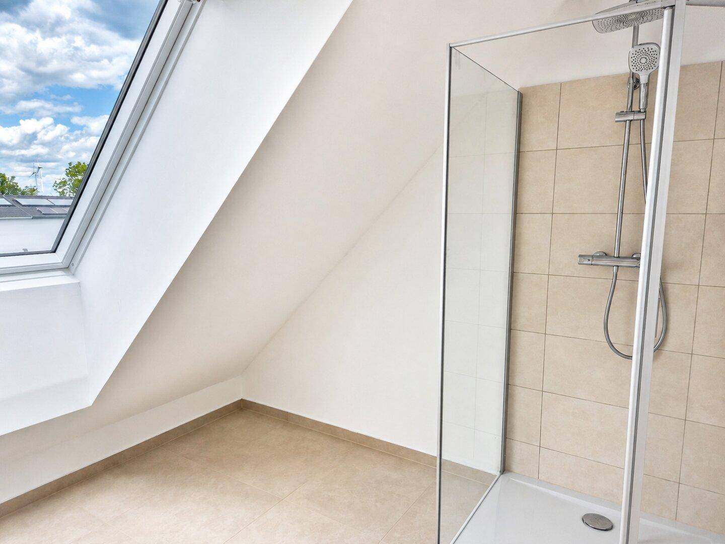 Modernes Badezimmer mit begehbarer Dusche, beigefarbenen Fliesen und einem Dachfenster für natürliches Licht.