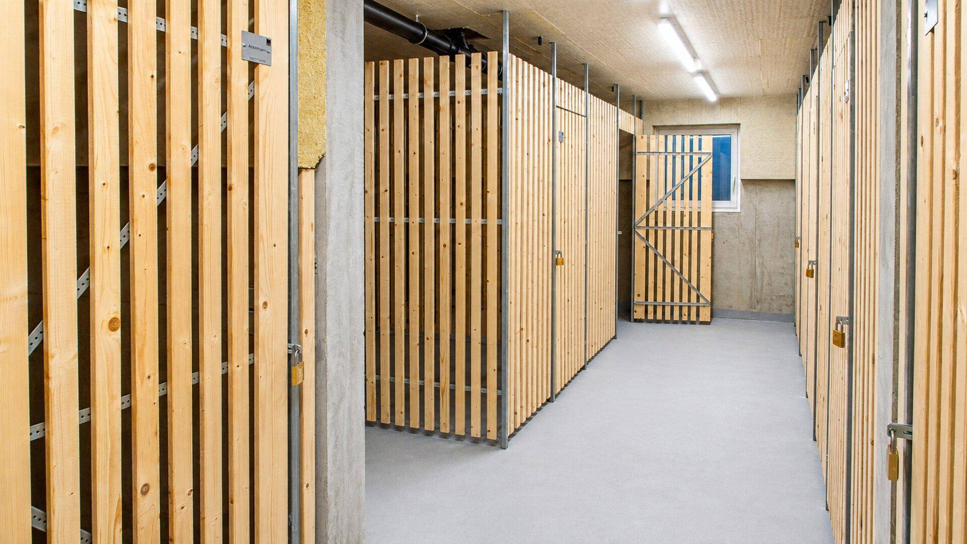 Geräumiger Kellerraum mit individuellen Holzverschlägen für zusätzlichen Stauraum.