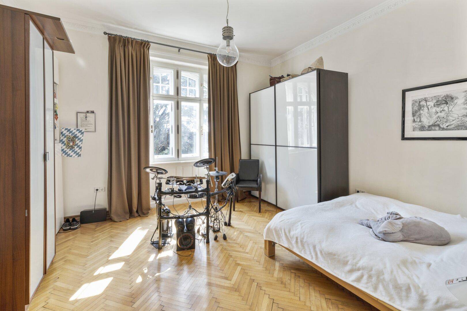 Helles Schlafzimmer mit Parkettboden, Kleiderschrank und Schlagzeug-Set.