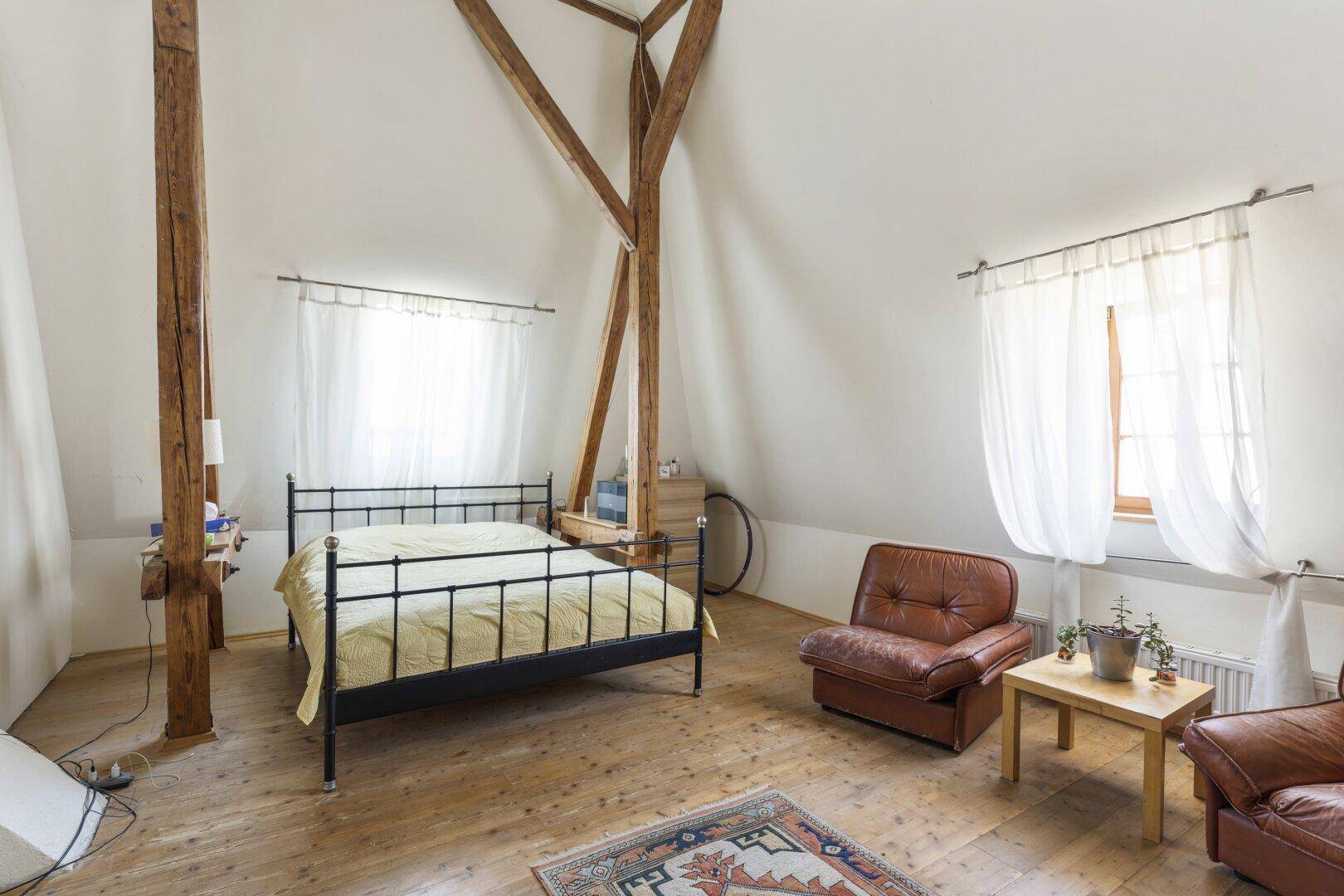 Gemütliches Schlafzimmer im Dachgeschoss mit Holzbalken und rustikalem Charme.
