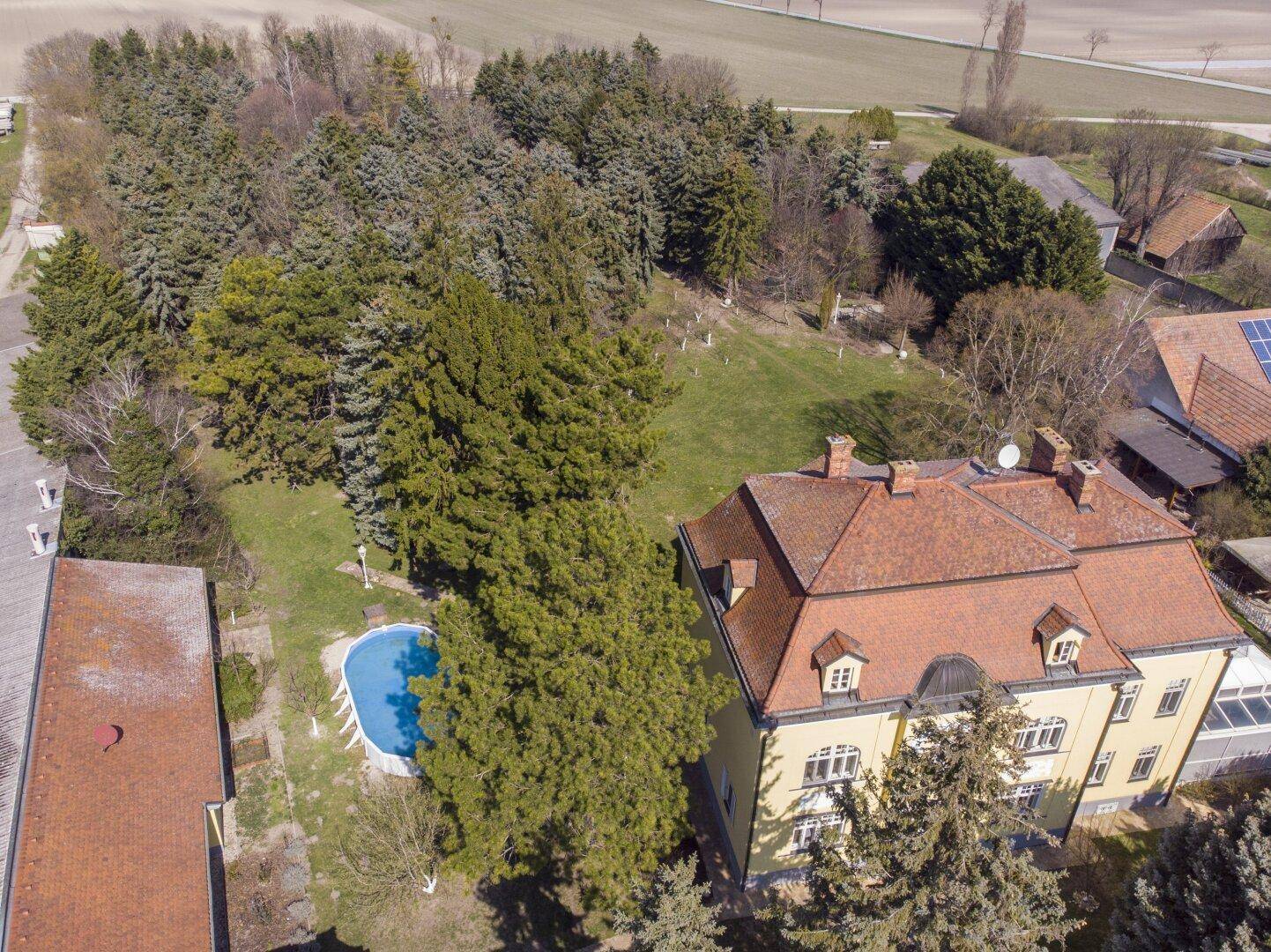 Luftaufnahme der Villa mit Pool und weitläufigem Grundstück, umgeben von Wald und Feldern.