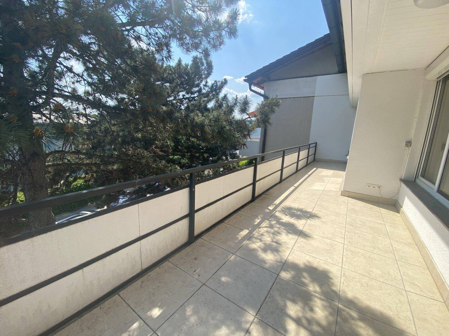 Langer Balkon mit Fliesenboden und Blick ins Grüne, ideal für Entspannung im Freien.