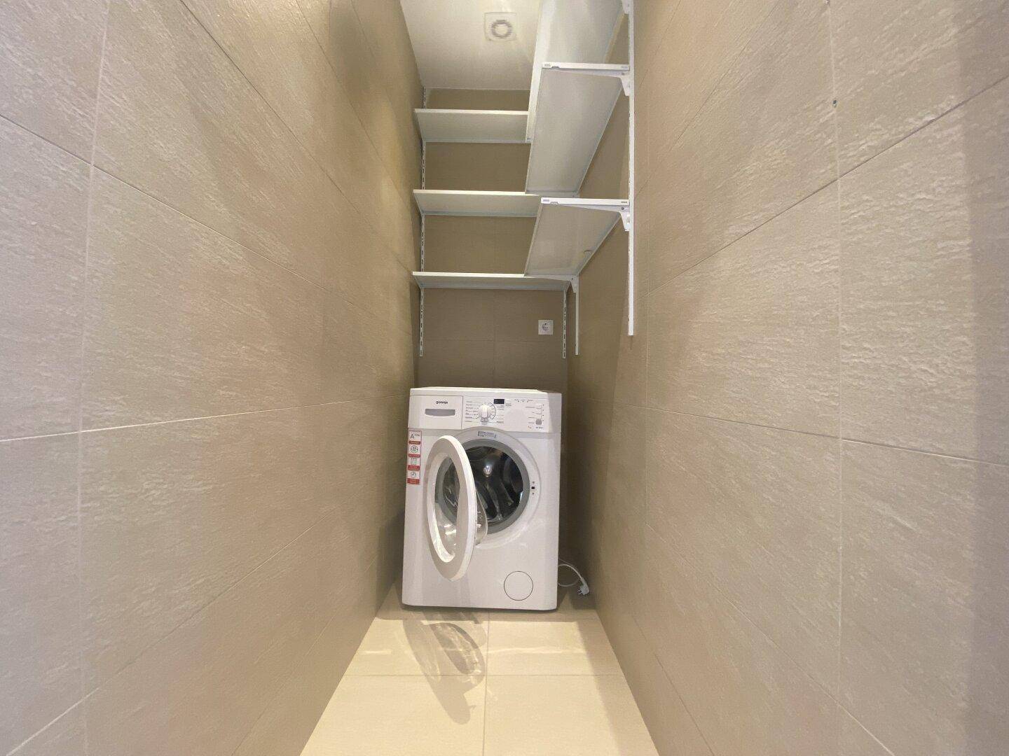 Praktischer Hauswirtschaftsraum mit Waschmaschine und Wandregalen für zusätzlichen Stauraum.