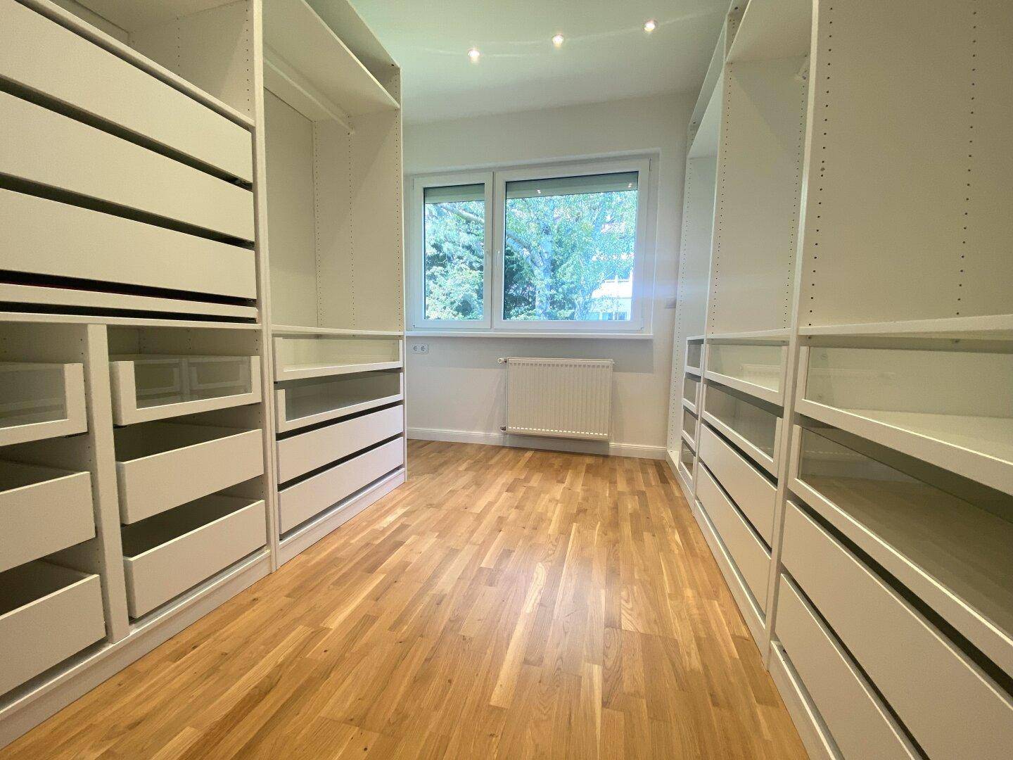 Geräumiger begehbarer Kleiderschrank mit vielen Schubladen und Regalen, ideal für Organisation.