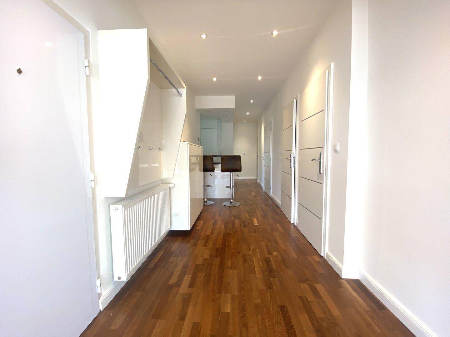 Heller Flur mit Holzparkettboden, Einbauschrank und modernen Türen.